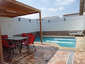 a patio with a table and chairs and a swimming pool at Cómoda casa con piscina in Arica