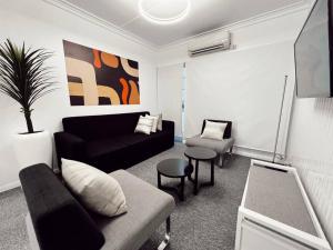 a living room with a black couch and a chair at Gladstone Gem 7 - Suva CBD 2 Bedroom Apartment in Suva