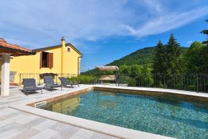a swimming pool with two chairs and a house at Villa Danica with pool - Perka in Zvoneće