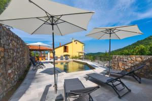 a patio with two white umbrellas and a pool at Villa Danica with pool - Perka in Zvoneće