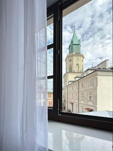 okno z widokiem na budynek z wieżą zegarową w obiekcie Brama Krakowska - Old Town - Premium Apartment w mieście Lublin