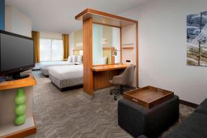 a hotel room with a bed and a desk and a television at SpringHill Suites Alexandria in Alexandria