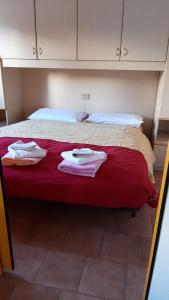un letto con lenzuola rosse e asciugamani bianchi di GRAYNITE-High Altitude Apartment a Passo del Tonale