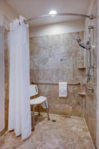 a bathroom with a shower with a chair and a shower curtain at Courtyard by Marriot Cranbury South Brunswick in Cranbury