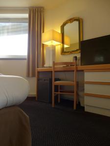 Habitación de hotel con escritorio y espejo en Hôtel Paradis, en Lourdes