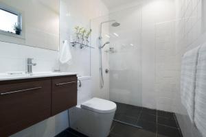 a white bathroom with a toilet and a shower at Zelman Cottage in Hepburn Springs