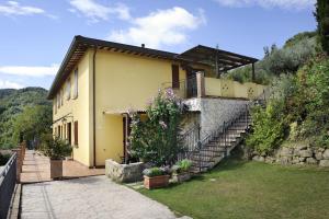 una casa gialla con scale e fiori in un cortile di Country House Il Sambro a Bettona