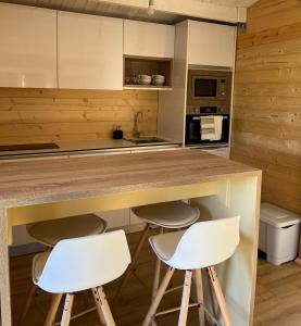 uma cozinha com dois bancos brancos num balcão em Casas de A Uriceira em Cangas
