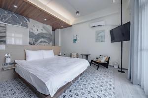 um quarto com uma cama grande e uma televisão de ecrã plano em Long Stay Here em Tainan