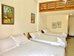 três camas num quarto com lençóis brancos em Villa Royal Palawan em Narra