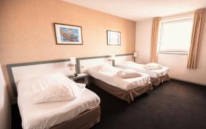 a hotel room with two beds and a window at Hôtel Paradis in Lourdes