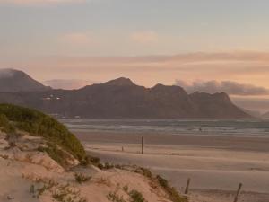 a view of a beach with mountains in the background at OysterCatcher Self-Catering Accommodation Strand in Cape Town
