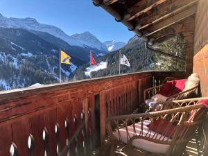 einen Balkon mit Stühlen und Flaggen auf einem Berg in der Unterkunft Charming Chalet with mountain view near Arosa for 6 People house exclusive use in Langwies