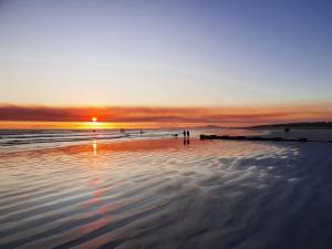a person standing on a beach at sunset at OysterCatcher Self-Catering Accommodation Strand in Cape Town