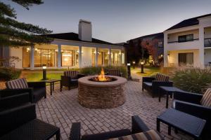 a patio with a fire pit and chairs and a building at Courtyard Detroit Southfield in Southfield