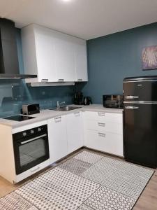 a kitchen with white cabinets and a black refrigerator at One bedroom apartment in central Savonlinna in Savonlinna