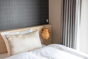 a bed with a white pillow next to a window at Oyado Kawaramachi Gojo（御宿 河原町五条） in Kyoto