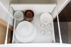 a white cabinet with plates and bowls in it at Oyado Kawaramachi Gojo（御宿 河原町五条） in Kyoto