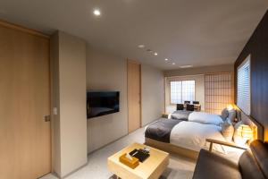 a bedroom with a bed and a couch and a tv at Oyado Kawaramachi Gojo（御宿 河原町五条） in Kyoto