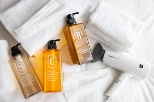 three bottles of sunscreen sitting on a bed at Oyado Kawaramachi Gojo（御宿 河原町五条） in Kyoto