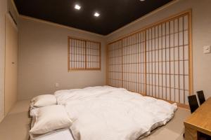 a large white bed in a room with a window at Oyado Kawaramachi Gojo（御宿 河原町五条） in Kyoto