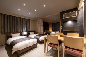 a hotel room with two beds and a table and chairs at Oyado Kawaramachi Gojo（御宿 河原町五条） in Kyoto