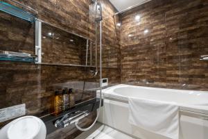 a bathroom with a tub and a toilet and a sink at Oyado Kawaramachi Gojo（御宿 河原町五条） in Kyoto