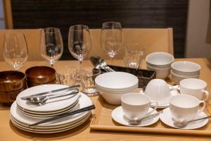 a table with white dishes and wine glasses on it at Oyado Kawaramachi Gojo（御宿 河原町五条） in Kyoto