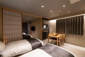 a hotel room with two beds and a table and a dining room at Oyado Kawaramachi Gojo（御宿 河原町五条） in Kyoto