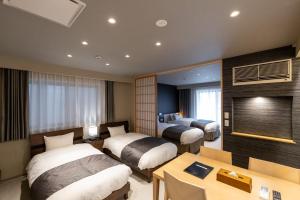 a hotel room with two beds and a table at Oyado Kawaramachi Gojo（御宿 河原町五条） in Kyoto