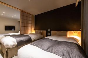 a bedroom with three beds and a black wall at Oyado Kawaramachi Gojo（御宿 河原町五条） in Kyoto