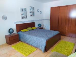 1 dormitorio con 1 cama con 2 almohadas amarillas en Casa da Nelita en São Martinho do Porto