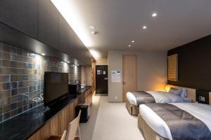 a hotel room with two beds and a flat screen tv at Oyado Kawaramachi Gojo（御宿 河原町五条） in Kyoto