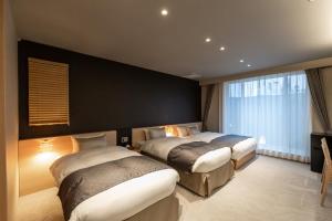 a bedroom with two beds and a black wall at Oyado Kawaramachi Gojo（御宿 河原町五条） in Kyoto