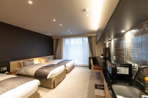 a hotel room with two beds and a sink at Oyado Kawaramachi Gojo（御宿 河原町五条） in Kyoto