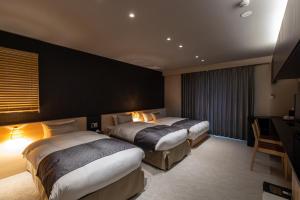 a hotel room with two beds and a television at Oyado Kawaramachi Gojo（御宿 河原町五条） in Kyoto