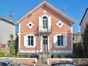 Uma mulher em frente a uma casa cor-de-rosa em Villa MAGDA à 30 mn mer pour vacances ou cure em Dax