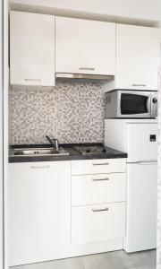 a white kitchen with white cabinets and a sink at Apartmani Boban in Živogošće