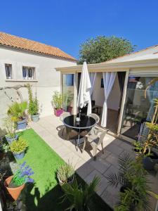 un patio con mesa, sillas y plantas en Escapade charentaise, en Aigrefeuille-dʼAunis