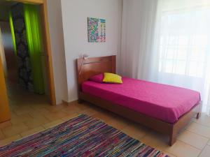 1 dormitorio con 1 cama con manta rosa y ventana en Casa da Nelita, en São Martinho do Porto
