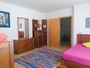 1 dormitorio con cama rosa y espejo en Casa da Nelita, en São Martinho do Porto