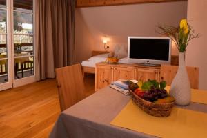 a living room with a television and a bowl of fruit on a table at Rosengartnerhof Apt Vorberg in Terlano