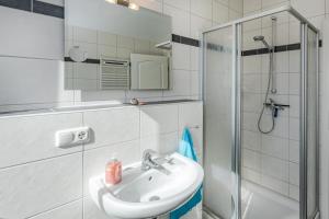 a white bathroom with a sink and a shower at Haus Ines in Korswandt +8 photos