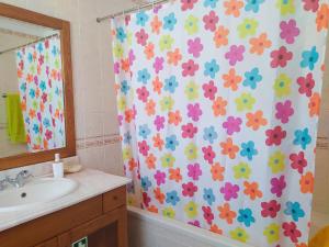 La salle de bains est pourvue d'un rideau de douche et de fleurs. dans l'établissement Casa da Nelita, à São Martinho do Porto