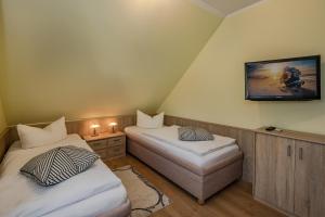 a room with two beds and a tv on the wall at Haus Ines in Korswandt