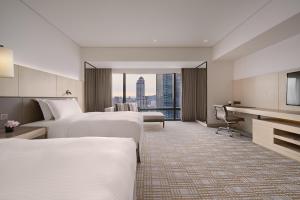 台北市にある台北マリオットホテルのベッド2台とデスクが備わるホテルルームです。