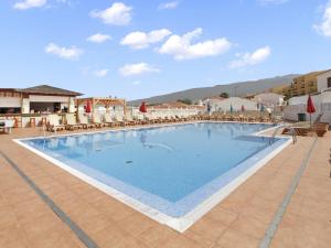 a large swimming pool in a resort with chairs at GOLDEN HOLIDAYS, Heated Pool, Air C, Internet, Parking in Adeje
