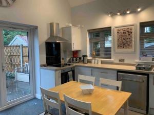 a kitchen with a wooden table and a table and chairs at Hedgehog Cottage in Bury Saint Edmunds