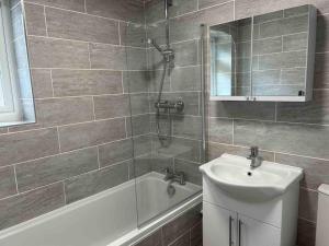 a bathroom with a tub and a sink and a shower at Hedgehog Cottage in Bury Saint Edmunds