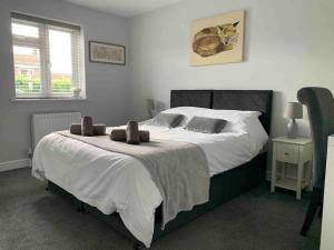 a bedroom with a large bed with white sheets at Hedgehog Cottage in Bury Saint Edmunds